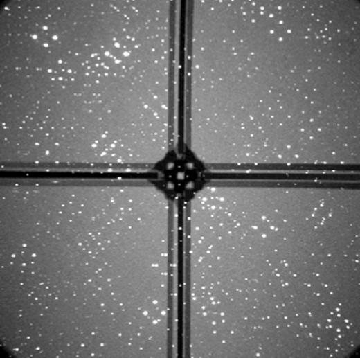 An example of a RoboPol image. Each point in the sky has been mapped to four spots on the CCD. A focal plane mask, held in place by four support legs, reduces the sky background level for the central target.